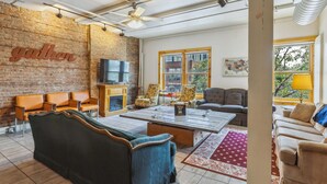 A spacious living area with a fireplace, seating, and a large window offering a view of the outside. - The Victor 2 - Cleveland's Urban Lodge (Cleveland)