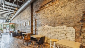 A restaurant with brick walls, wooden tables, and chairs. - The Victor 2 - Cleveland's Urban Lodge (Cleveland)