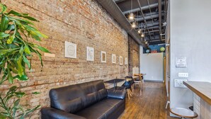 A modern interior with a brick wall, a black leather sofa, wooden flooring, and a bar area. - The Victor Full - Cleveland's Urban Lodge - Sleep 51! (Cleveland)
