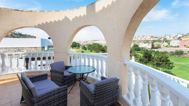 A balcony with wicker furniture and a glass table, overlooking a green landscape and buildings. - CH Villa San Miguel La Marquesa Golf (Ciudad Quesada) (Ciudad Quesada)