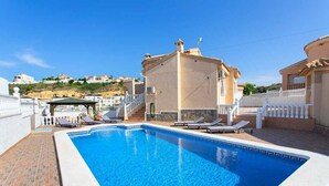 A swimming pool with lounge chairs, a covered seating area, and a building with a white fence and steps leading up to it. - CH Villa San Miguel La Marquesa Golf (Ciudad Quesada) (Ciudad Quesada)