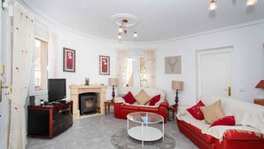 A living room with a fireplace, red sofas, a TV, and a round coffee table. - CH Villa San Miguel La Marquesa Golf (Ciudad Quesada) (Ciudad Quesada)