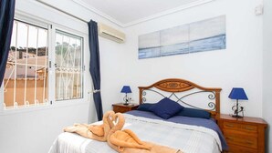 A bedroom with a bed, two bedside tables with lamps, a window with curtains, and a painting on the wall. - CH Villa San Miguel La Marquesa Golf (Ciudad Quesada) (Ciudad Quesada)