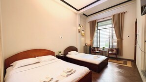 A hotel room with two beds, a small table, a chair, and a window with curtains. - Bê Tông Residences Homestay (Can Tho)