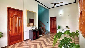 A hallway with wooden herringbone flooring, a ceiling fan, and a chandelier. - Bê Tông Residences Homestay (Can Tho)