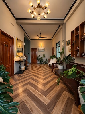 A hotel lobby with a herringbone patterned floor, a chandelier, ceiling fan, and wooden furniture. - Bê Tông Residences Homestay (Can Tho)