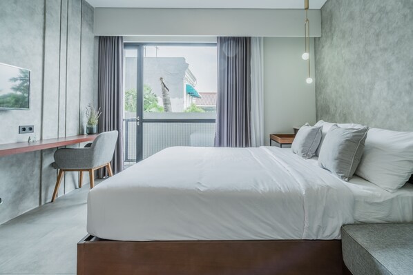 A modern bedroom with a large bed, a desk, and a chair. - 107 House Syariah (Jakarta)