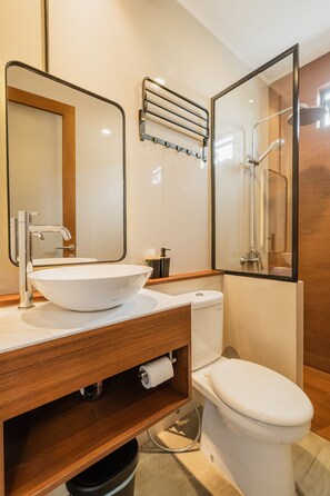 A modern bathroom with a large mirror, a white sink, a toilet, and a shower area. - 107 House Syariah (Jakarta)