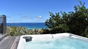 A hot tub with a clear view of the ocean and distant islands.