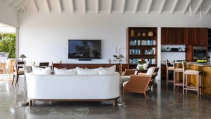 Un salon moderne avec un canapé blanc, un téléviseur à écran plat et une bibliothèque.