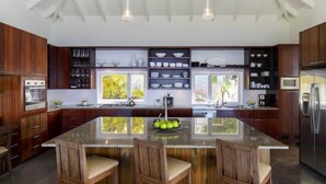 Une cuisine moderne avec des meubles en bois, un îlot central doté de tabourets de bar et une grande fenêtre qui laisse entrer la lumière naturelle.