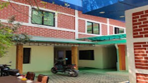 Un edificio de ladrillo con un patio cubierto, una mesa y dos motocicletas estacionadas afuera.