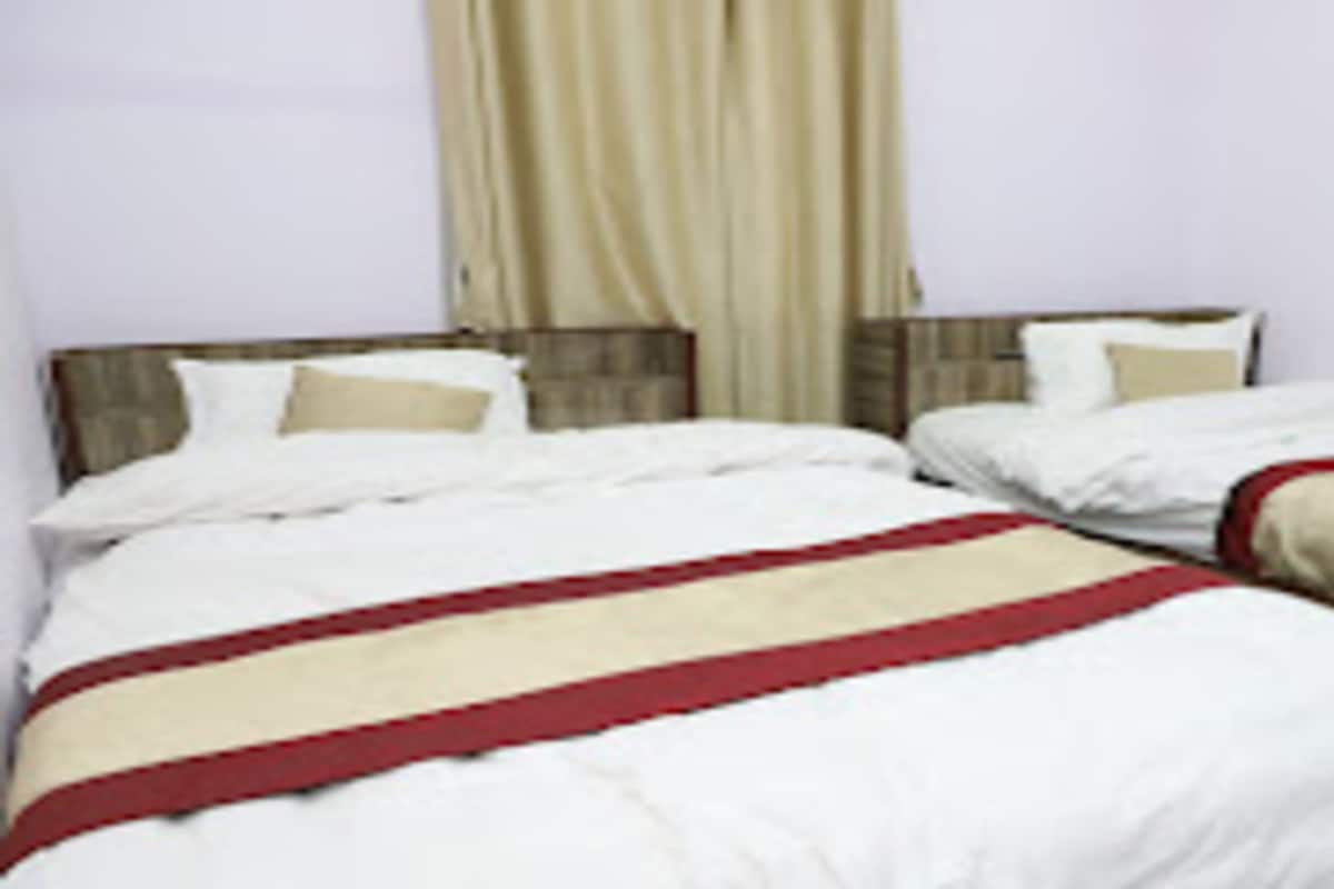 Una habitación de hotel con dos camas, cada una con ropa blanca y una franja roja.