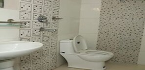 A bathroom with a white sink, toilet, and wall-mounted electrical outlets. - MeroStay 216 Hotel Manishankar (Kathmandu)
