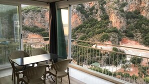 Een balkon met een tafel en stoelen, met uitzicht op een bergachtig landschap.