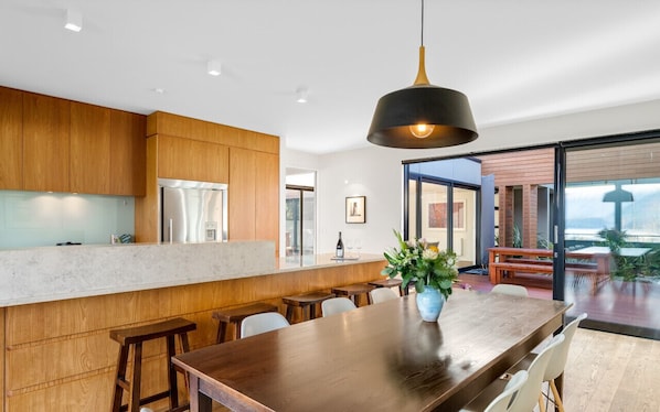 Une cuisine moderne avec des meubles en bois, un grand îlot central doté de tabourets et un luminaire suspendu.