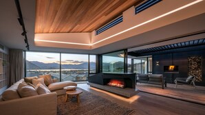 Una sala de estar moderna con chimenea, ventanas amplias y vistas a montañas.