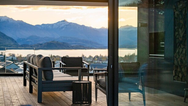 Un espacio exterior moderno con asientos y vistas a montañas y un lago.
