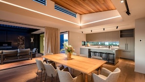 Una cocina moderna con una isla central, una zona de comedor con una mesa y sillas de madera, y una sala de estar con un sofá y una televisión.
