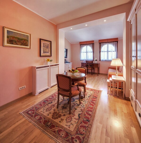 Un comedor con una mesa de madera, sillas y una alfombra. Hay una zona de cocina con armarios y una encimera.