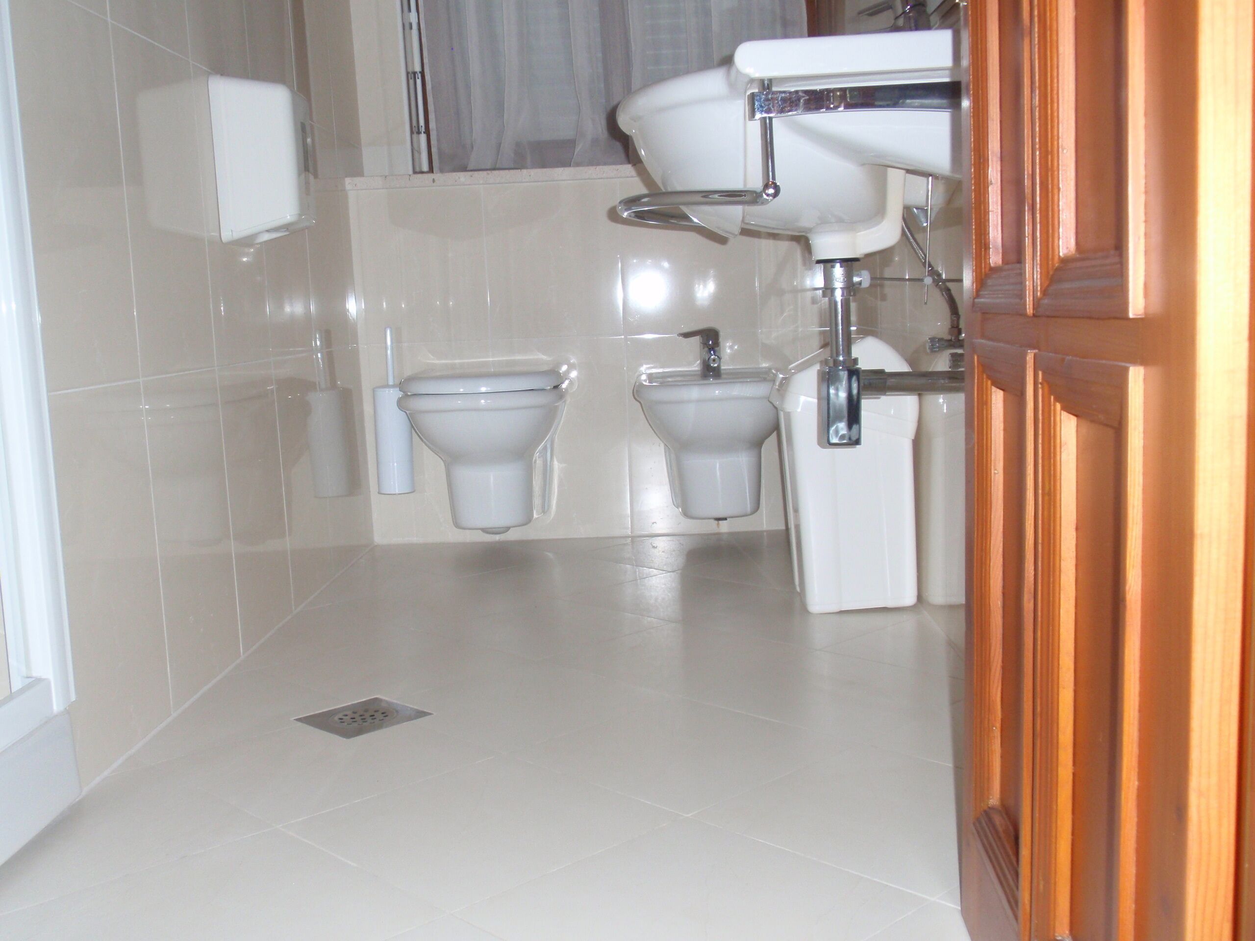 Un baño con dos inodoros, un lavamanos y dispensador de papel higiénico.