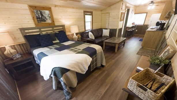 Ein gemütliches Blockhäuschen-Interieur mit Bett, Sofa, Essbereich und Küche.
