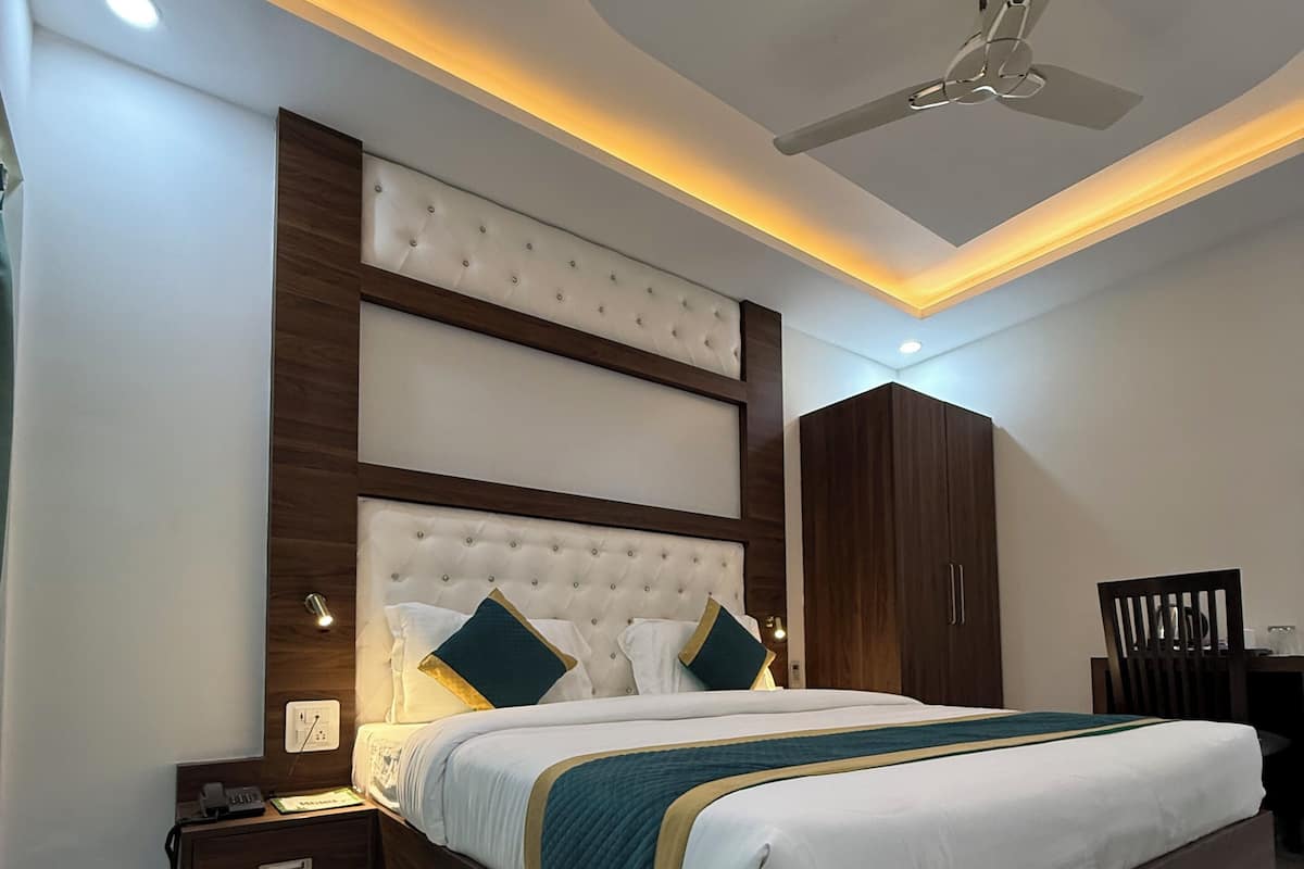 A modern bedroom with a large bed, wooden headboard, and a ceiling fan.