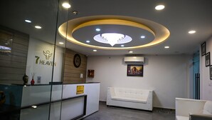 Un espace d’accueil comprenant un comptoir de réception, une horloge, un tableau encadré et un canapé blanc.