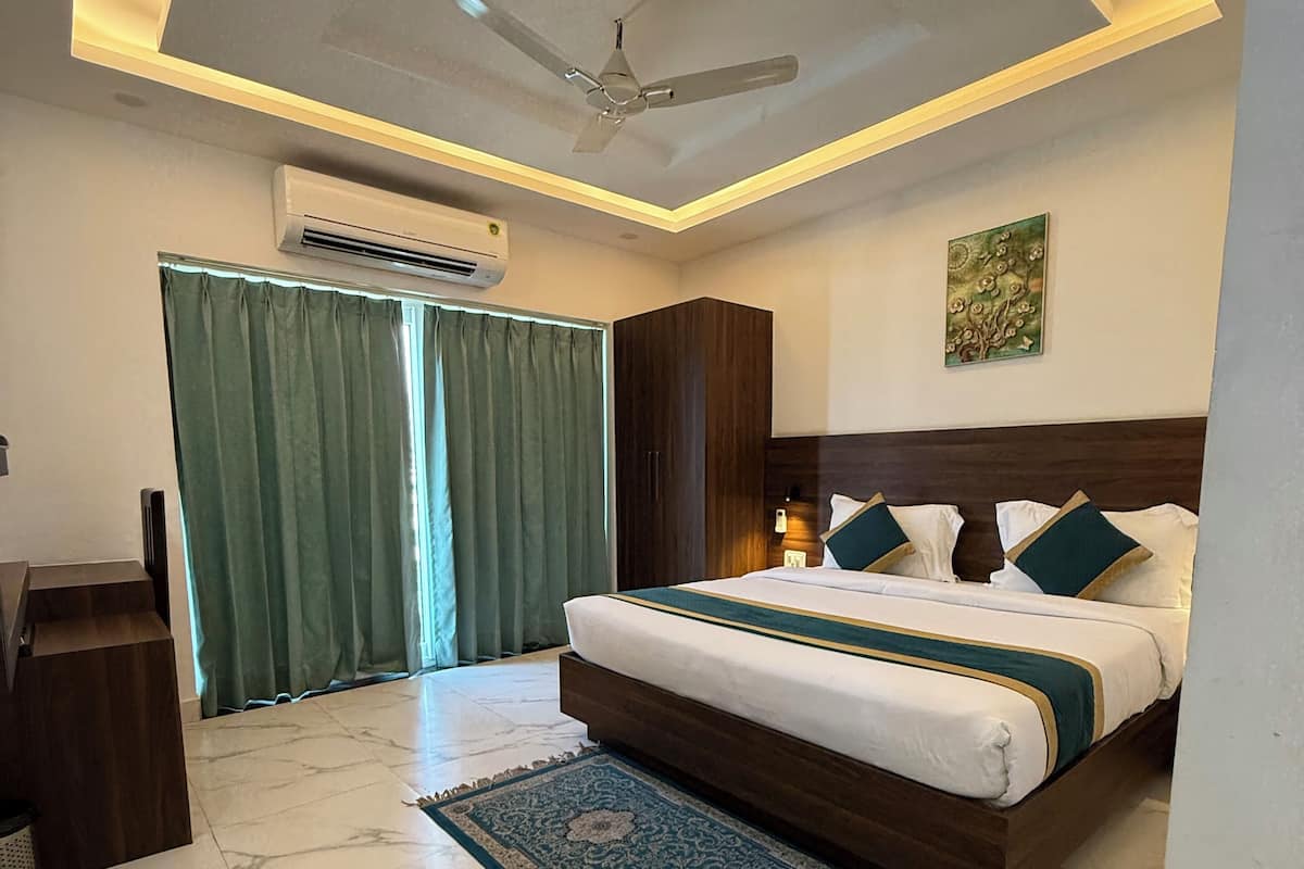 A modern bedroom with a large bed, a ceiling fan, an air conditioning unit, a green curtain, and a decorative painting on the wall.
