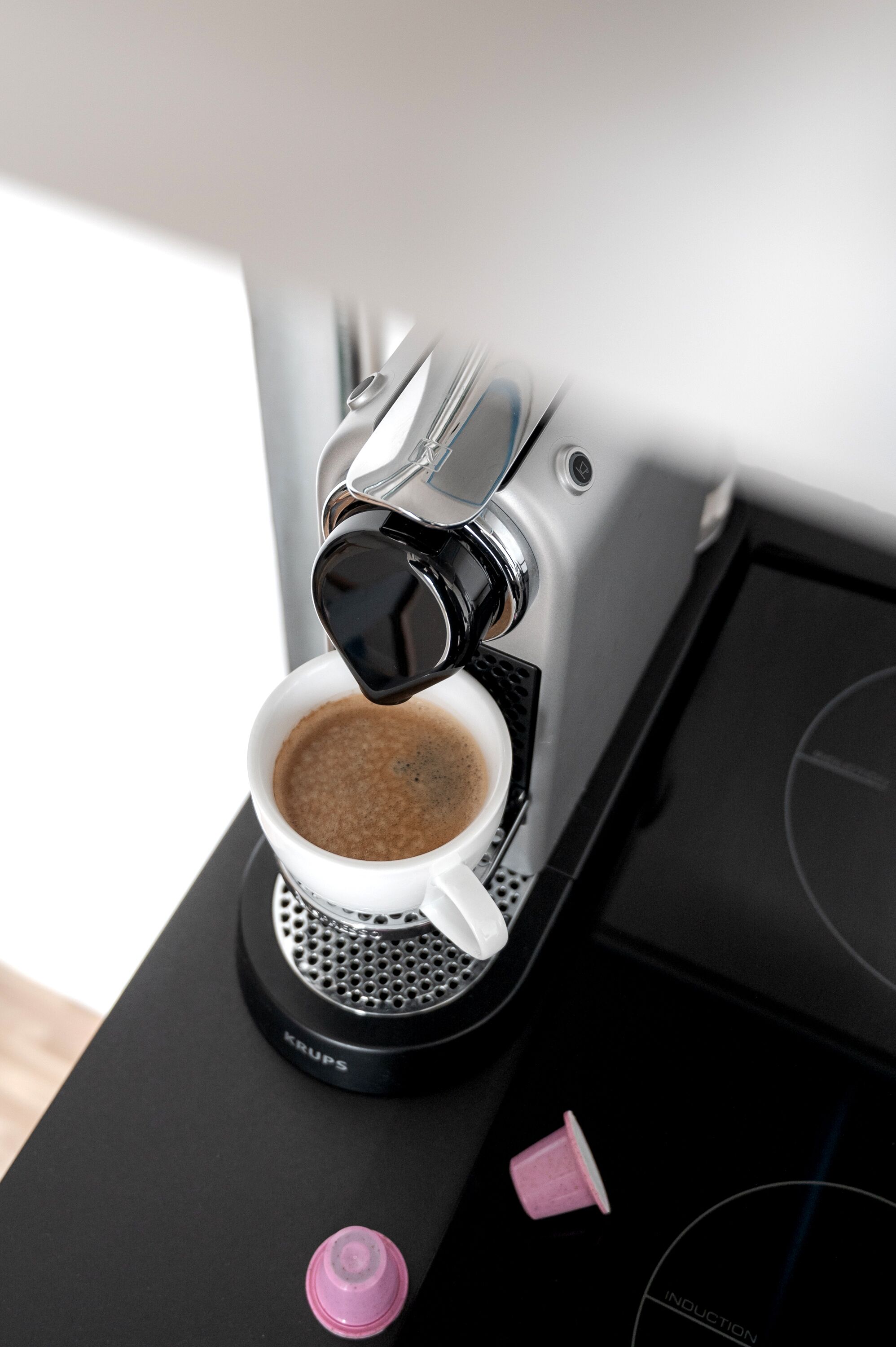 A Krups coffee machine dispensing coffee into a white cup.