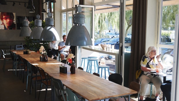 Un restaurante con una larga mesa de madera, sillas azules y lámparas colgantes.