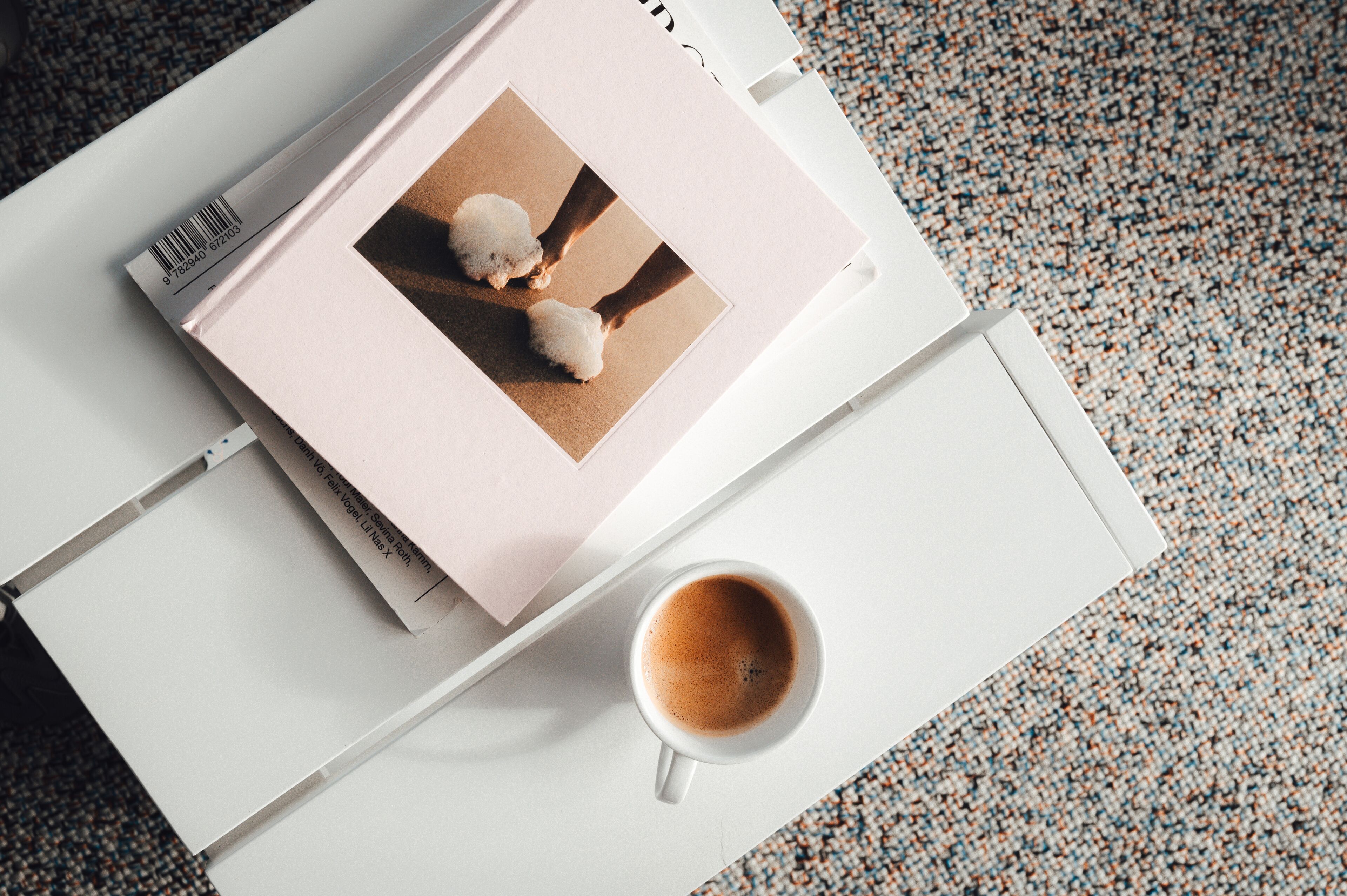 Un cuaderno blanco con una imagen de un perro esponjoso en una página, una taza de café y una alfombra con textura.