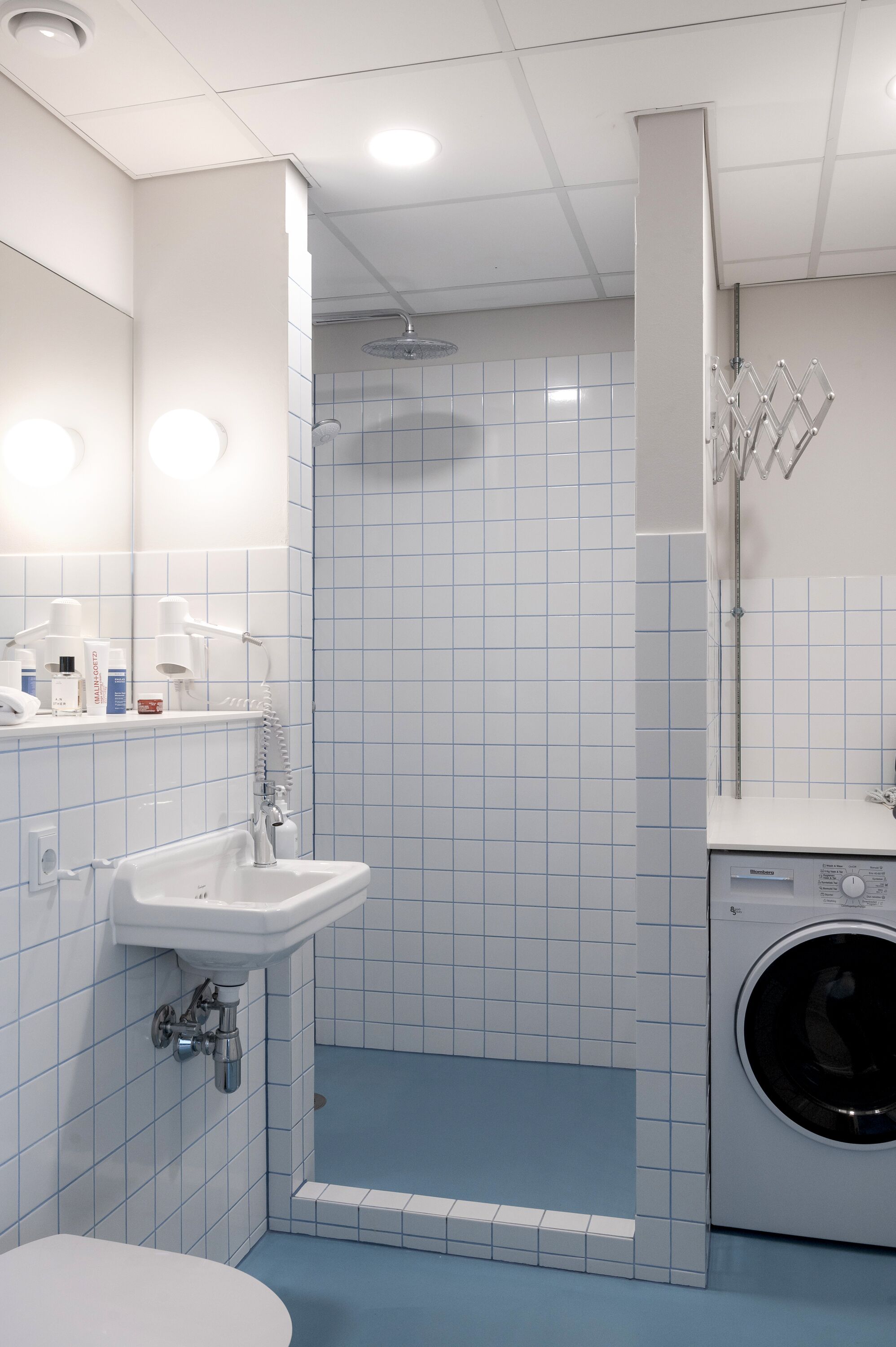 Une salle de bain équipée d’un lavabo, d’un miroir et d’un lave-linge.