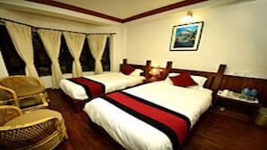 A hotel room with two beds, a chair, a nightstand, and a painting on the wall. - MeroStay 218 HK HE (Nagarjun)