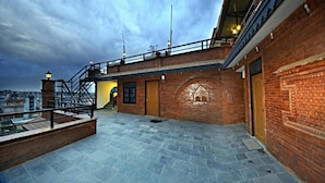A rooftop terrace with a brick wall, a wooden door, and a metal railing. - MeroStay 218 HK HE (Nagarjun)