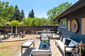 An outdoor patio area with a sofa, chairs, a table, and a fire pit.