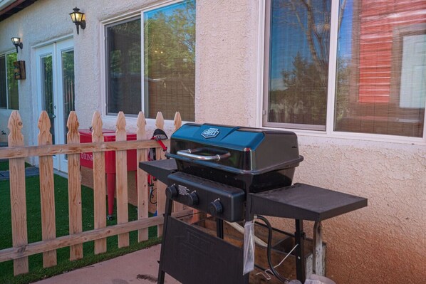 A barbecue grill set up on a patio with a wooden fence and a house in the background. - The Mona With RV and Boat Parking (Henderson)