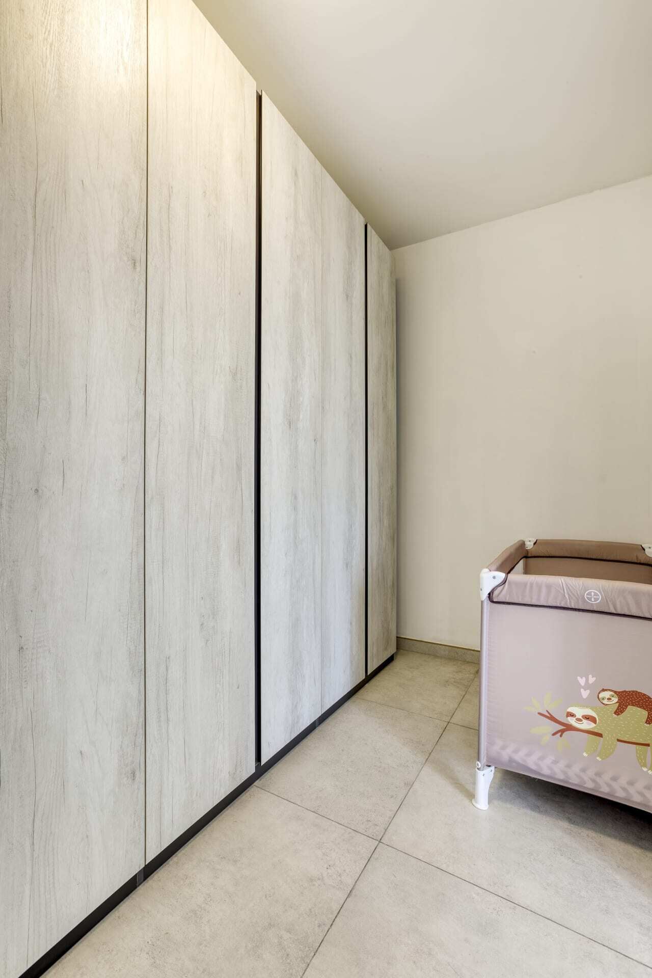 A room with a large wardrobe, a slatted ceiling, and a bed with a cartoon design.