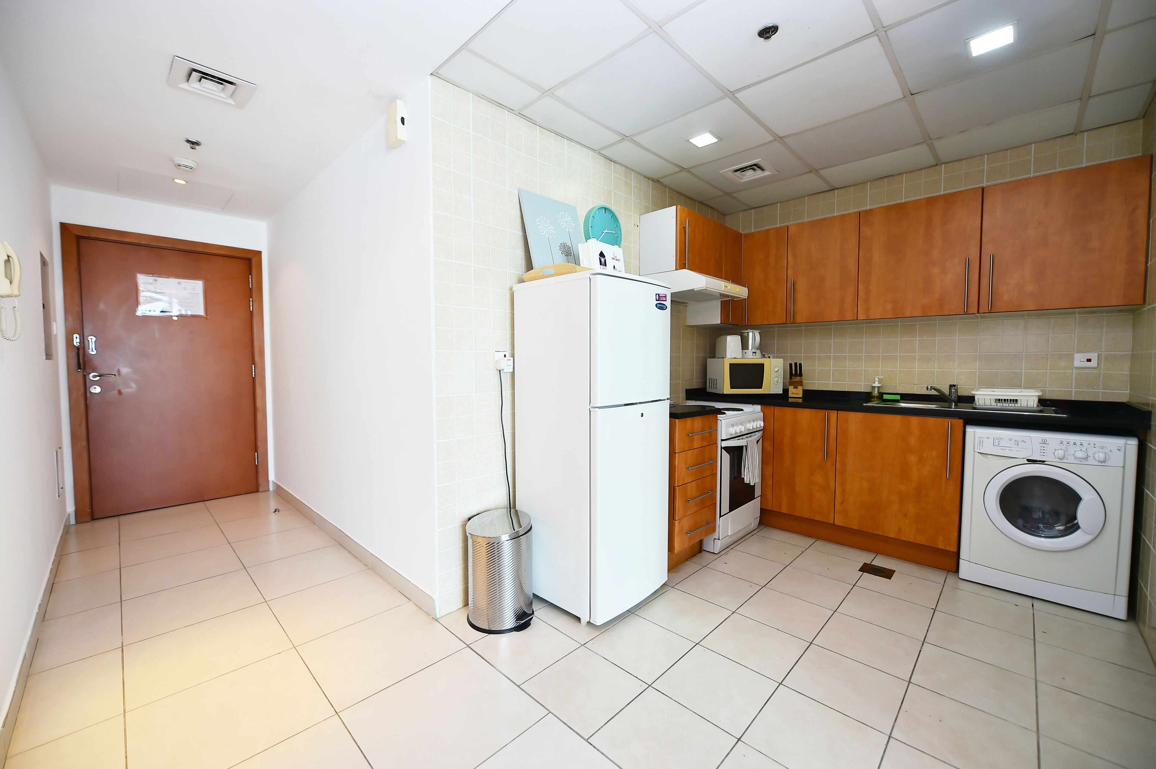 A kitchen with a refrigerator, microwave, oven, and washing machine.