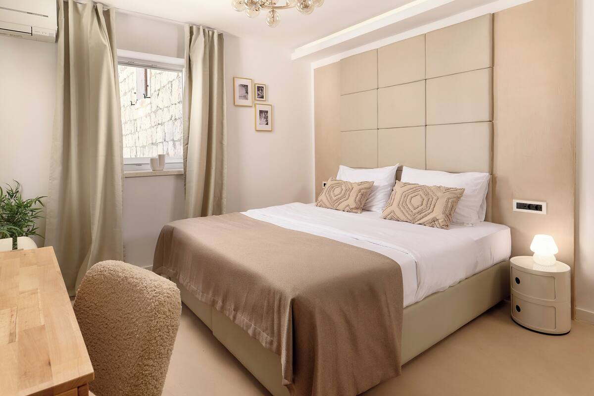 Een slaapkamer met een bed, nachtkastje en een raam met gordijnen.