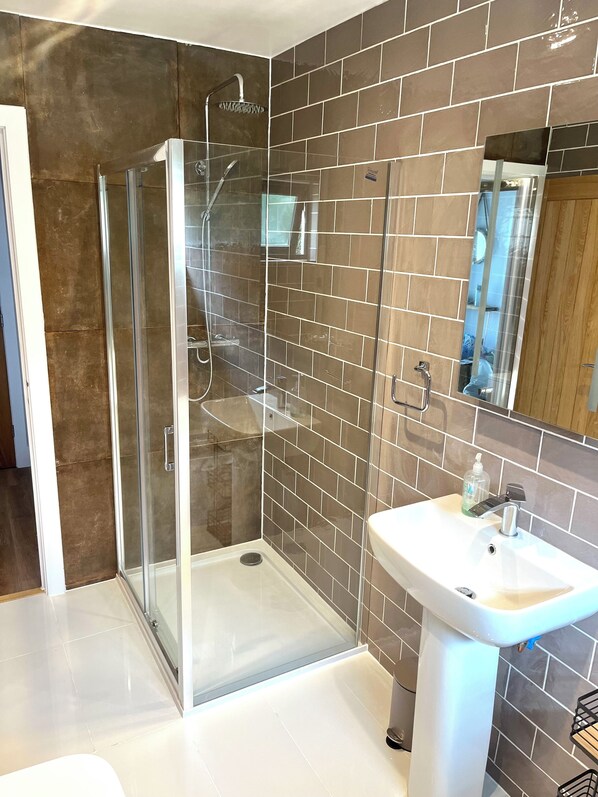 A modern bathroom with a glass-enclosed shower, a white sink, and a mirror above it. - Detached 3 bed 3 bath home 7 mins walk to Padstow Harbour- Pet Friendly Parking (Padstow)