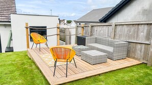 A patio area with a wooden deck, a sofa set, two chairs, and a small table.