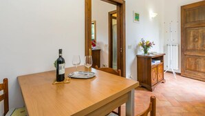 Un comedor con una mesa de madera, sillas, una botella de vino y copas.