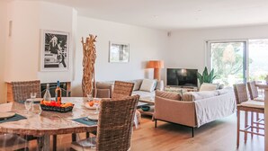 Un salon moderne comprenant un coin repas, un canapé, un téléviseur et une grande fenêtre.