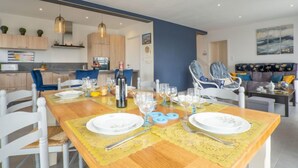 Un comedor moderno con una mesa de madera dispuesta para cuatro personas, rodeada de sillas blancas.