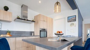 Una cocina moderna con una isla central, armarios de madera y una lámpara colgante.