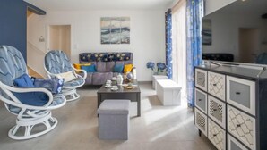 Una sala de estar moderna con un sofá, dos sillones, una mesa de centro y un mueble con puertas decoradas.