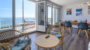 Ein geräumiger Balkon mit Meerblick, möbliert mit Korbstühlen und einem runden Tisch.