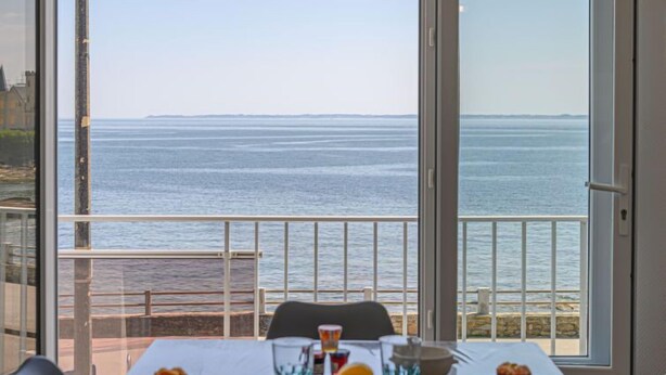 Ein Esstisch mit Meerblick, ein Balkon mit Geländer und ein Stuhl.