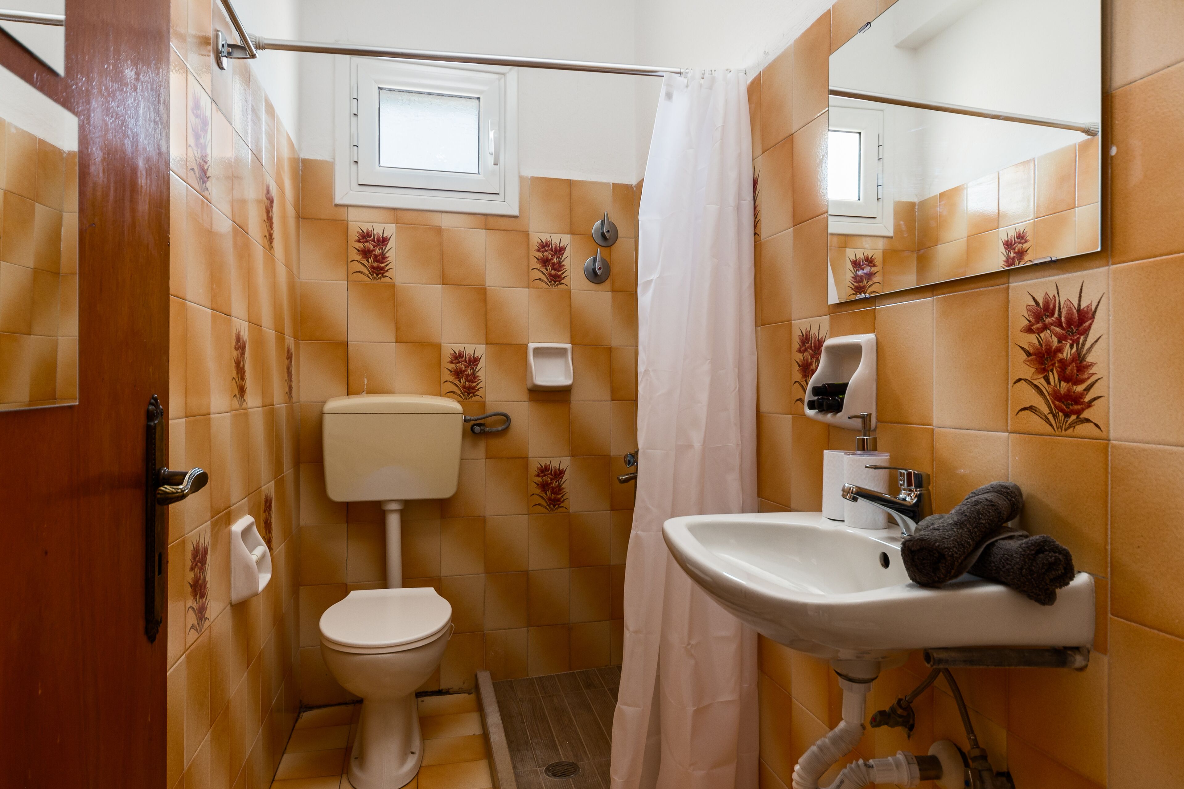 Un baño con inodoro, lavamanos y cortina de ducha.